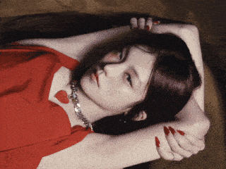 a woman in a red dress is laying down with her arms over her head