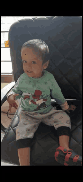a little boy wearing a green shirt with a bear on it