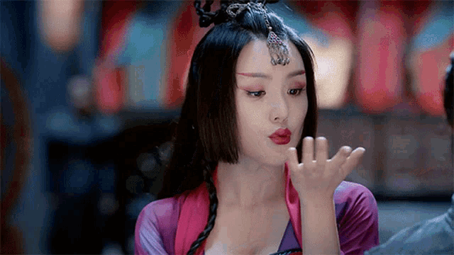 a woman blowing a kiss while wearing a purple top