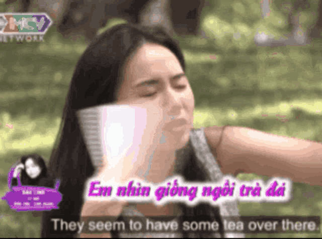 a woman talking on a cell phone with the words they seem to have some tea over there behind her