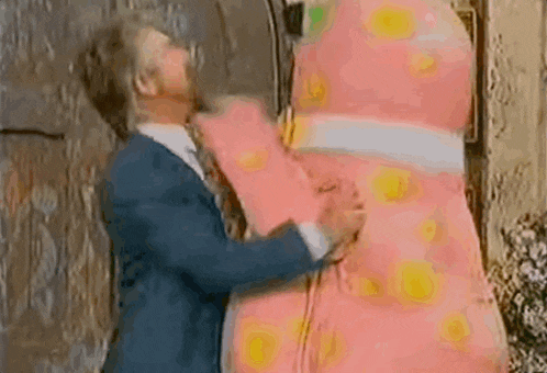 a man in a suit and tie is hugging a large pink stuffed animal .