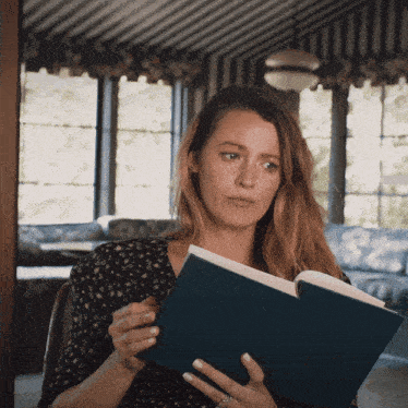 a woman is reading a book in a room with striped walls