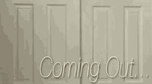 a man wearing glasses is peeking out from behind a door with the words `` coming out '' written on it .