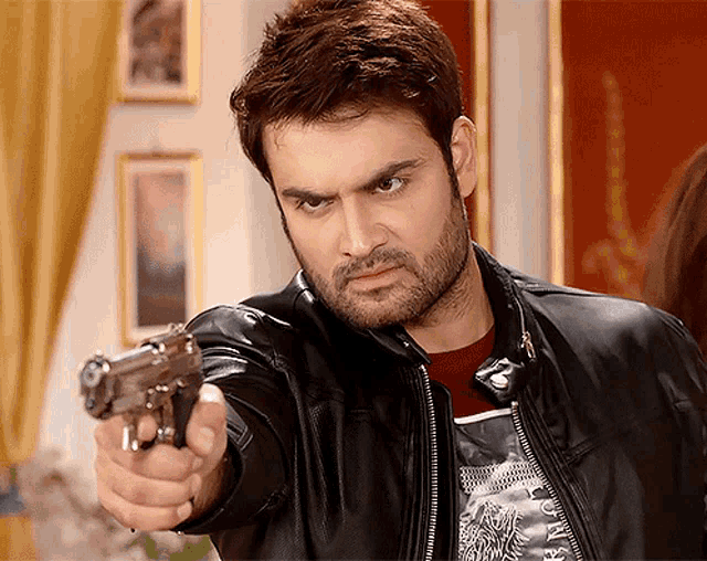 a man in a black leather jacket points a gun at the camera