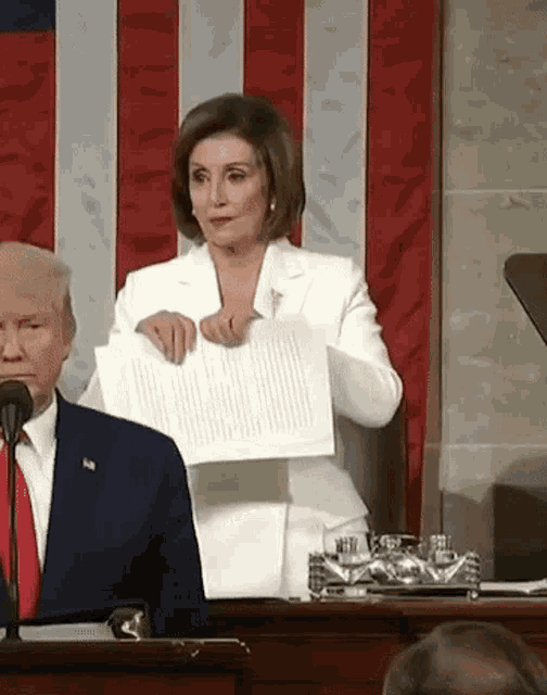 a woman is holding a piece of paper in front of a man in a suit and tie .