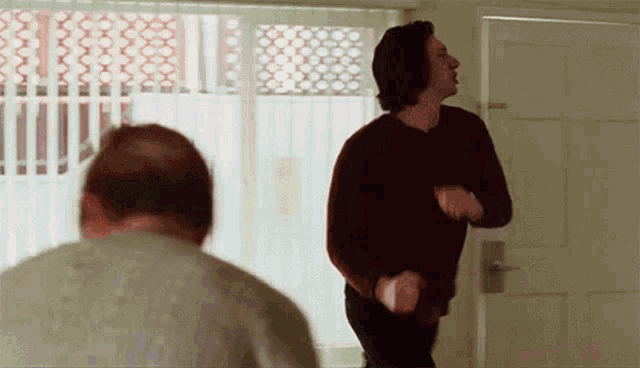 a man in a black sweater stands in front of a door