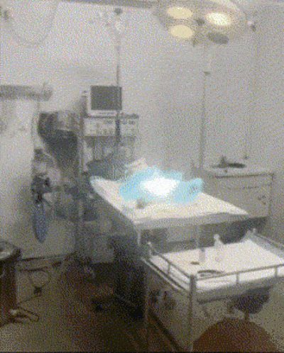 an operating room with a monitor on the wall above a bed