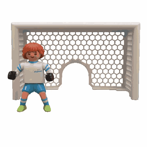 a playmobil soccer player is jumping to catch a soccer ball in a goal .