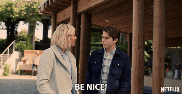 a man and a woman are standing next to each other and the man says " be nice "