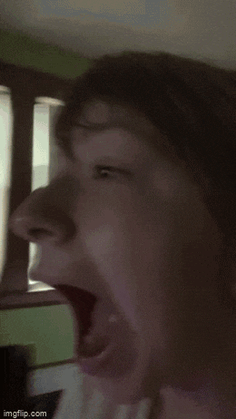 a close up of a person 's face with their mouth open and a window in the background