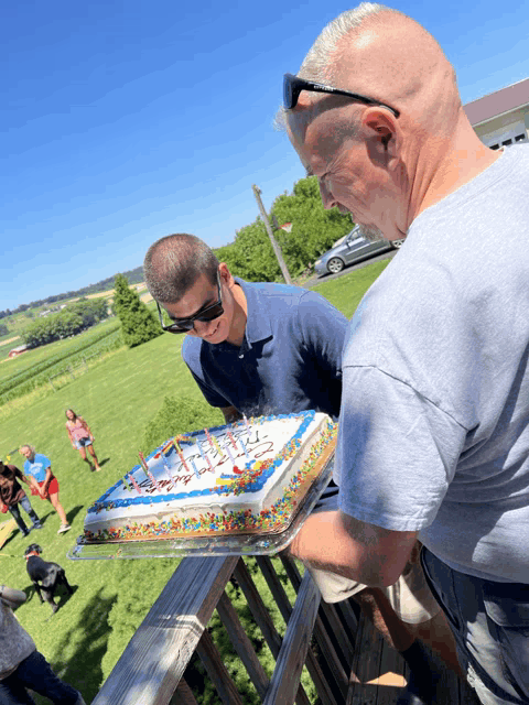 a man holds a birthday cake with candles and sprinkles