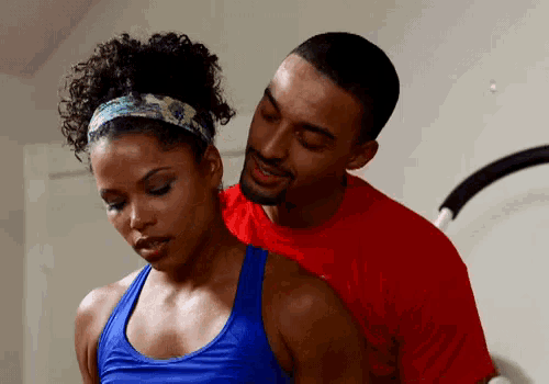 a man in a red shirt is touching a woman 's back