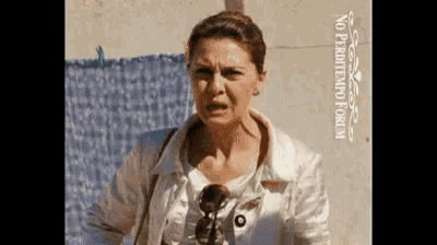 a woman wearing sunglasses and a white jacket is standing in front of a sign that says no perditempoforum