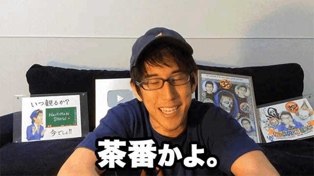 a man wearing glasses and a hat is sitting on a couch in front of a sign that says matsuman shaw