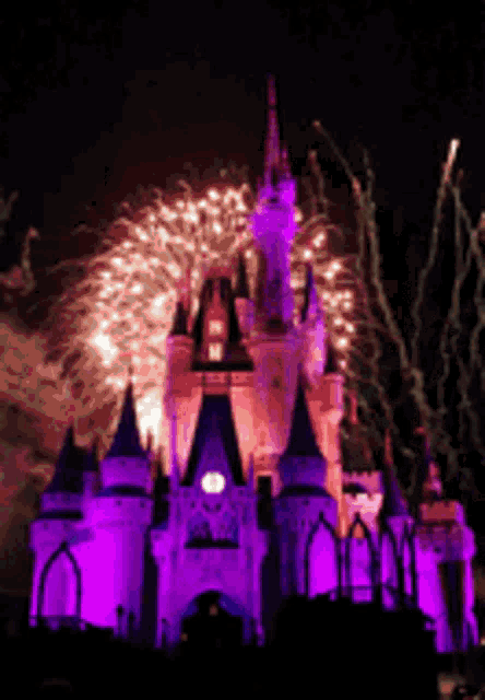 a castle is lit up with purple lights and fireworks are displayed in the background