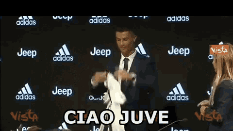a man in a suit and tie is holding a ronaldo jersey