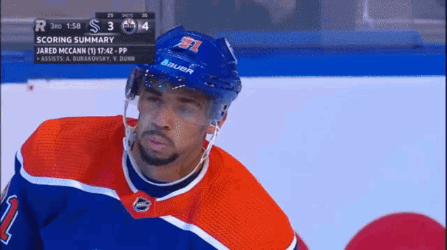 a hockey player wearing a blue bauer helmet stands on the ice