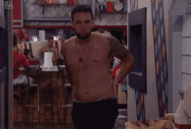 a shirtless man is standing in a hallway with a cbs logo on the wall