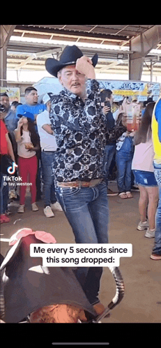 a man wearing a cowboy hat is dancing in front of a crowd of people .