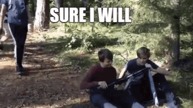 two boys are sitting on the ground in the woods holding a gun and a sign that says sure i will .