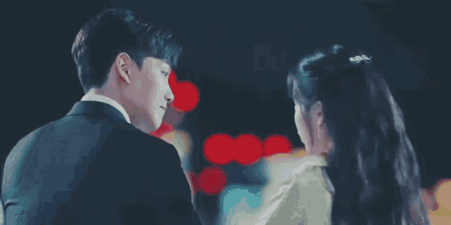 a man in a suit and a woman in a white dress are looking at each other .