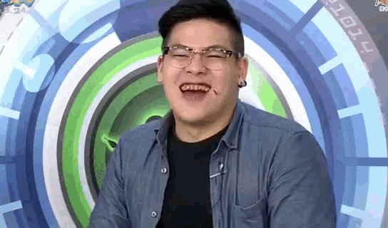 a man wearing glasses and a black shirt is laughing in front of a circle .