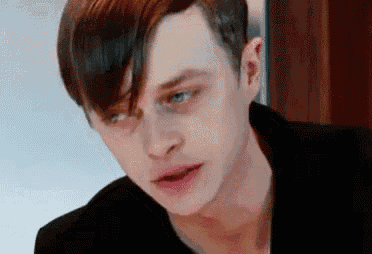 a close up of a young man 's face with a black jacket on .