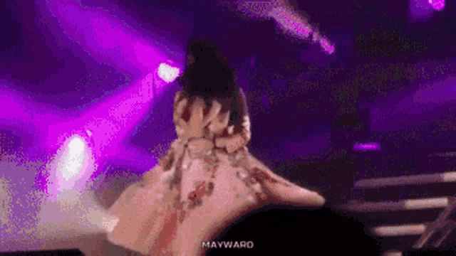 a woman in a pink dress is dancing on a stage in front of a crowd .