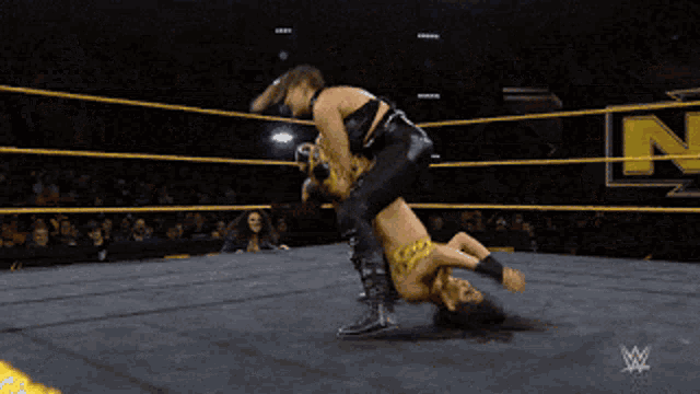 a wrestling match is going on in a ring with a wwe logo in the corner