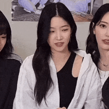 a group of women are sitting next to each other in a room . one of the women is wearing a white jacket .