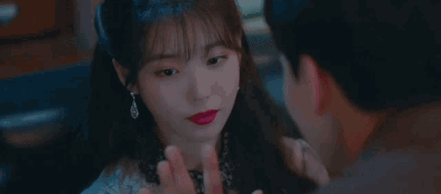 a man and a woman are touching each other 's faces . the woman is wearing red lipstick and earrings .