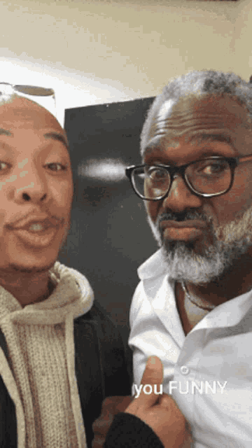 a man with glasses and a beard stands next to another man with the caption you funny