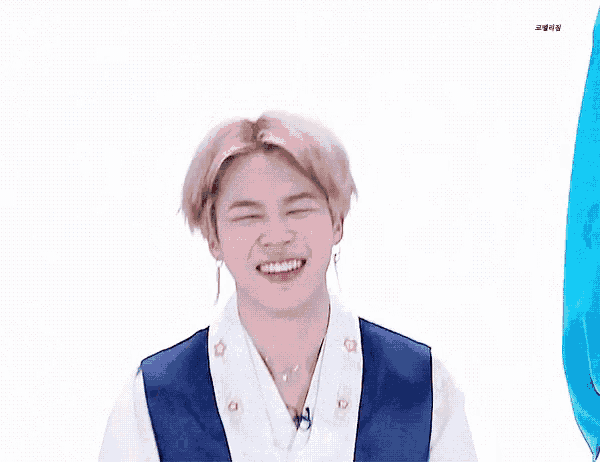 a person wearing a blue vest and white shirt making a heart with their hands