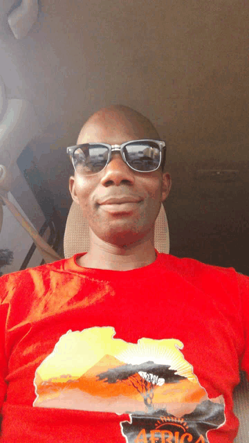a man wearing sunglasses and a red africa shirt