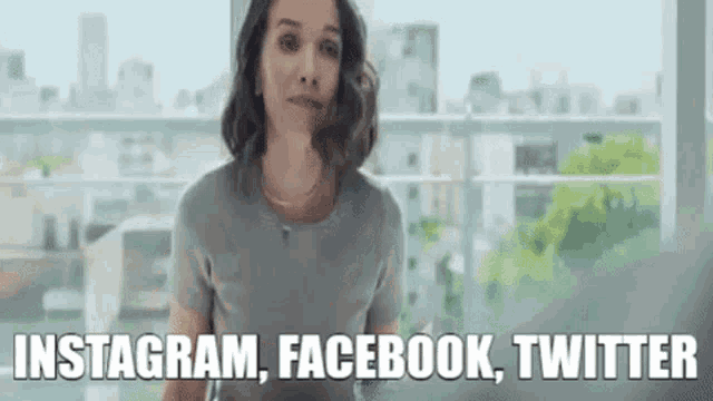 a woman is standing in front of a window with the words instagram , facebook , twitter written above her .