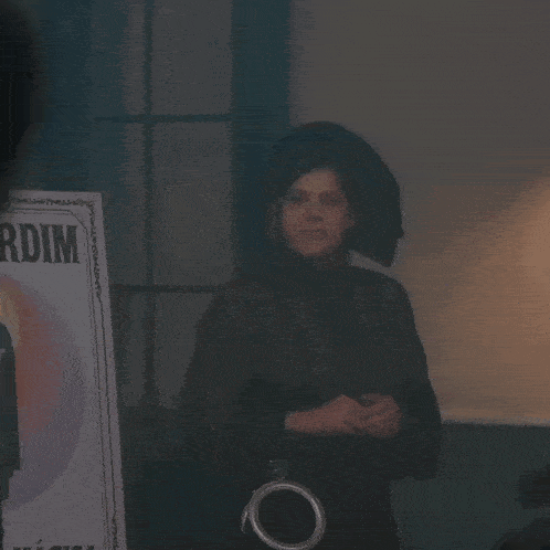 a woman wearing a hat and a purse is standing in front of a window .