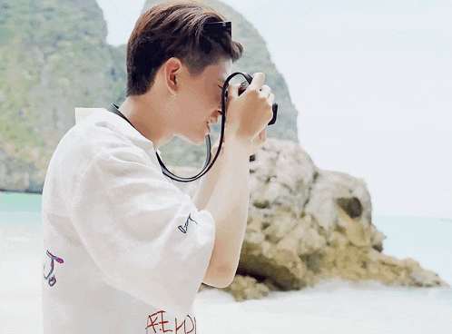 a man taking a picture with a camera with a shirt that says fly on it