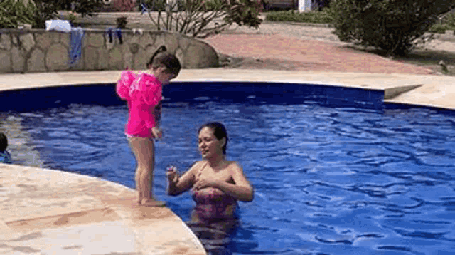 a woman and a little girl are playing in a pool .