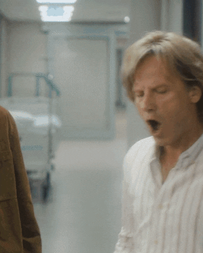 a man yawning in a hospital hallway with his mouth open