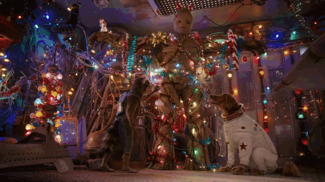 a dog in a space suit is standing next to a robot covered in christmas lights