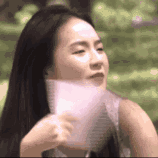 a close up of a woman holding a piece of paper in front of her face .