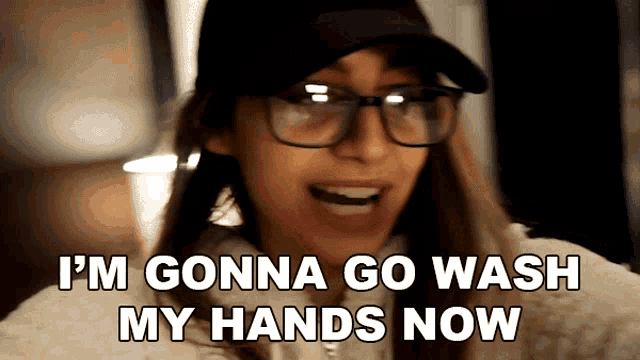 a woman wearing glasses and a hat is saying i 'm gonna go wash my hands now