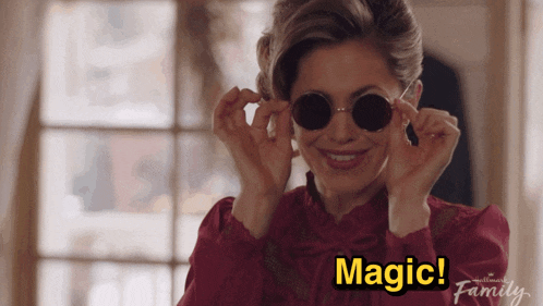 a woman wearing round sunglasses is smiling with the words magic above her