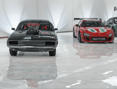 a black car with a turbo on the front is next to a red car