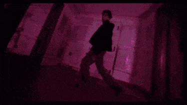 a man is dancing in a hallway with purple lights