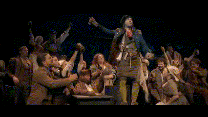 a man in a military uniform is surrounded by a crowd of people on a stage