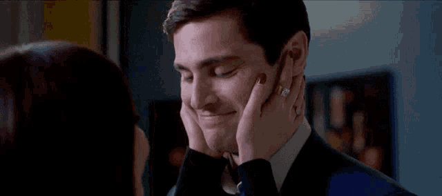 a woman is touching the face of a man in a suit