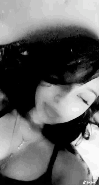 a black and white photo of a woman with her eyes closed and a necklace on .