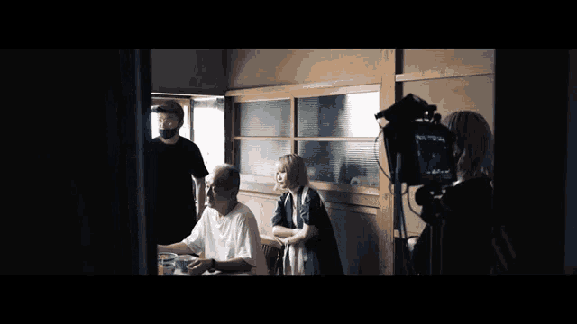 a group of people are sitting at a table while a cameraman takes a picture