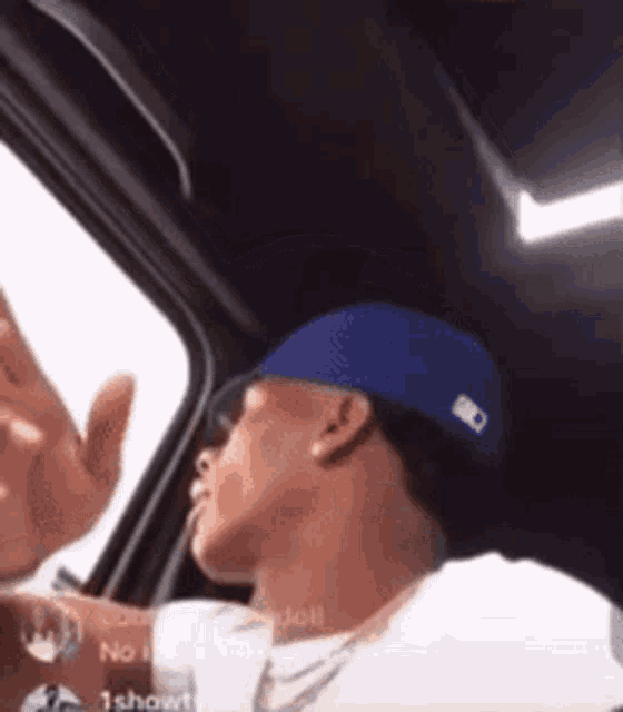 a man wearing a blue hat is sitting in a car and waving .